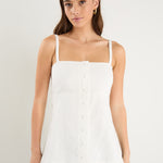 Woman wearing a fitted ivory vest top with thin straps, front buttons, and a clean, tailored silhouette.