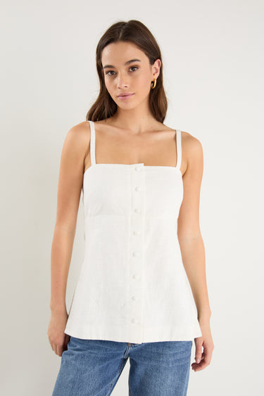 Woman wearing a fitted ivory vest top with thin straps, front buttons, and a clean, tailored silhouette.