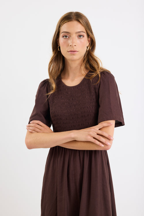 Woman wearing a brown dress with a plain white background