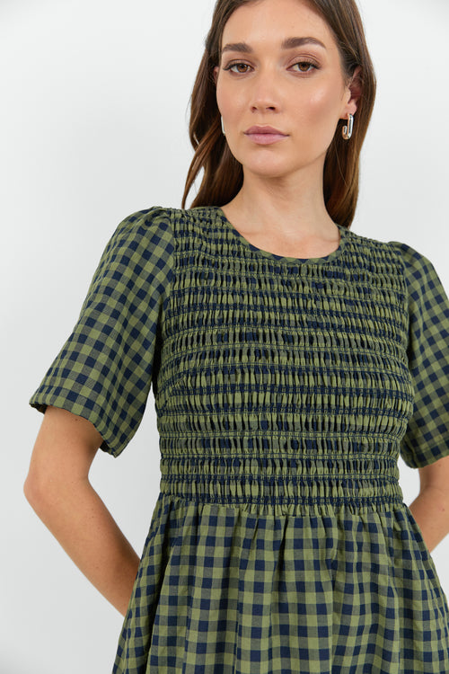 Woman wearing a green and blue checkered dress against a white background