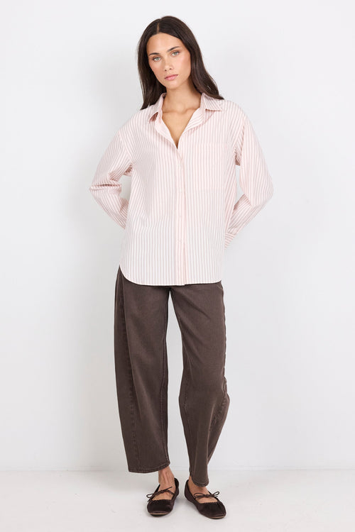 Woman wearing a light pink striped shirt and brown pants on a white background