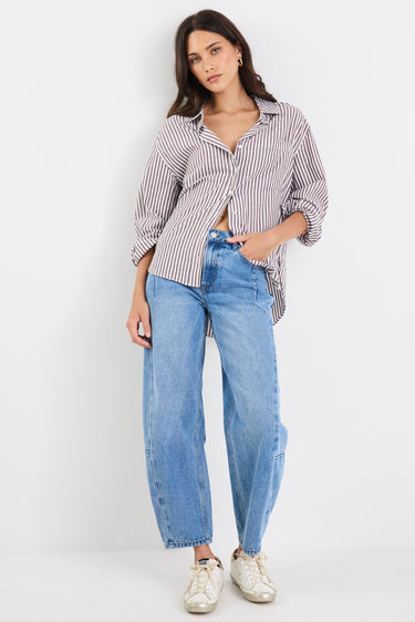 Woman wearing a striped shirt and blue jeans on a white background
