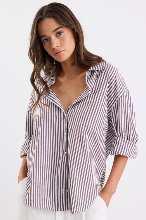 Relaxed fit striped shirt with chocolate and white stripes, deep V-neck collar, and rolled-up sleeves, paired with ivory shorts.