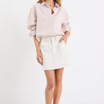 Woman wearing a light pink shirt and white skirt on a white background