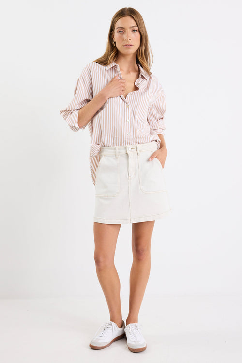 Woman wearing a light pink shirt and white skirt on a white background