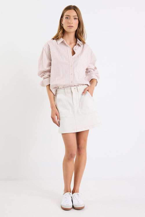 Woman wearing a light pink shirt and white skirt on a white background