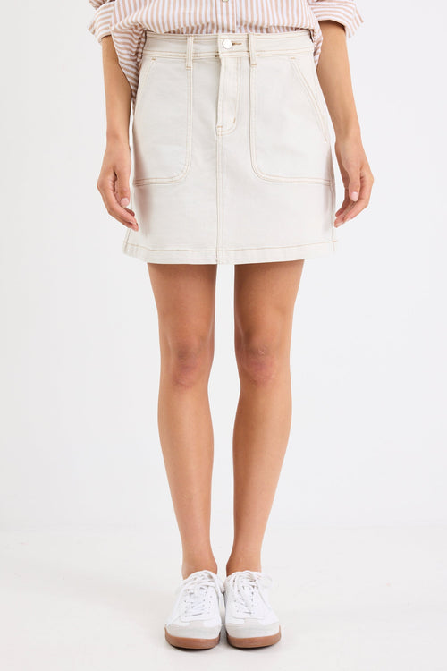 Person wearing a white denim skirt with a plain background
