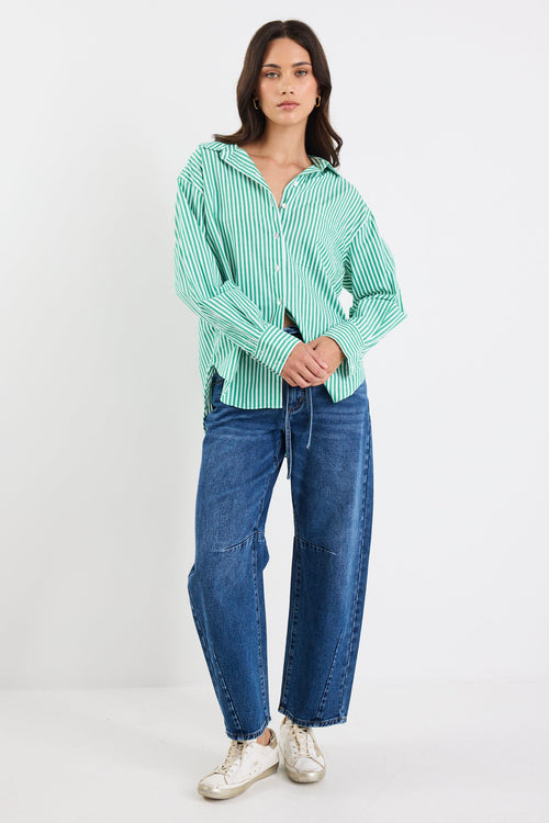 Woman wearing a green striped shirt and blue jeans on a white background