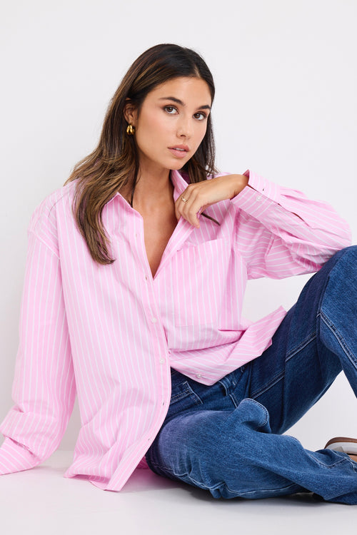 model wears a pink and white stripe shirt with dark blue jeans