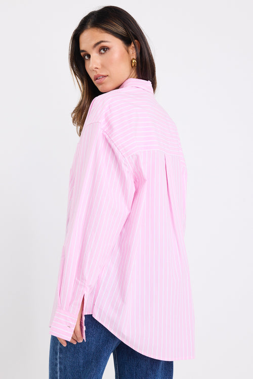 model wears a pink and white stripe shirt with dark blue jeans