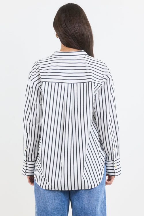 Person wearing a black and white striped shirt with blue jeans on a white background