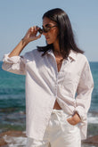 Woman in a white striped shirt and pants standing by the ocean