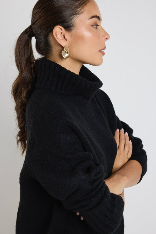 model wears a black knit with blue jeans