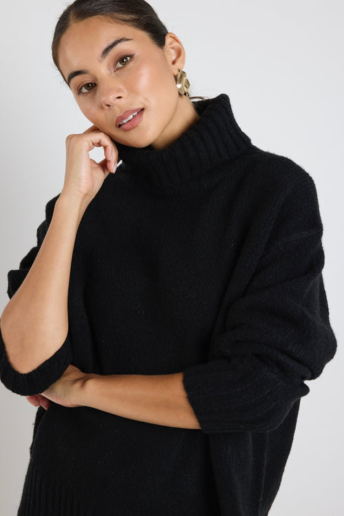 model wears a black knit with blue jeans