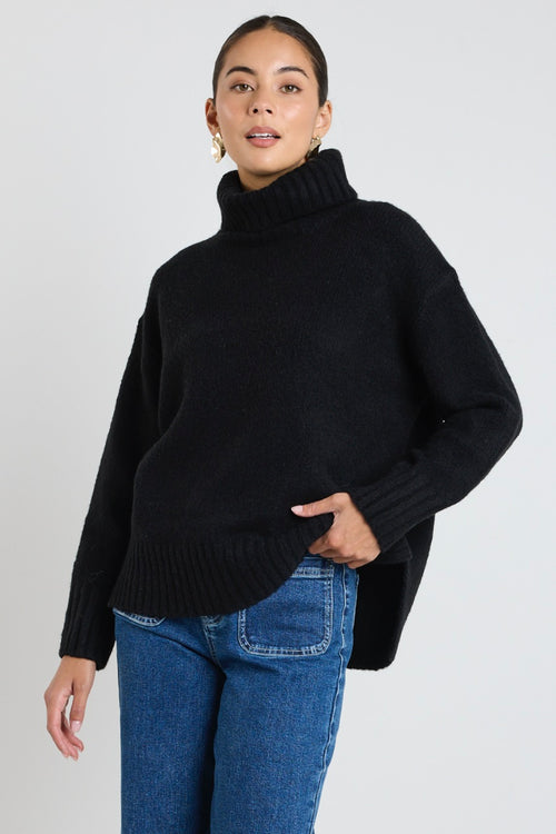 model wears a black knit with blue jeans