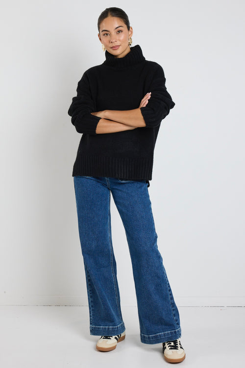  model wears a black knit with blue jeans
