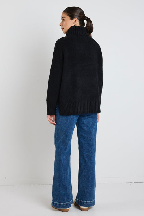 model wears a black knit with blue jeans