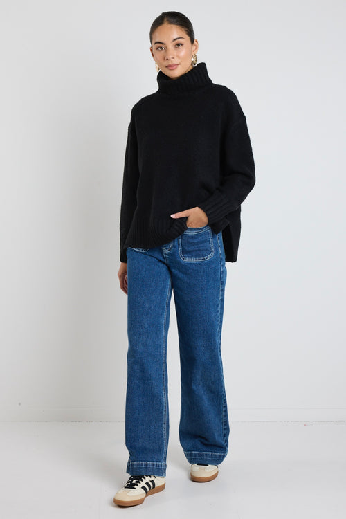 model wears a black knit with blue jeans