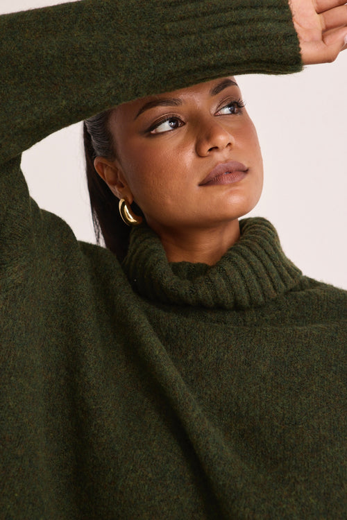 model wears a green turtle neck knit