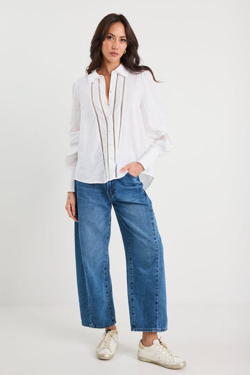 Woman wearing a white blouse and blue jeans on a white background