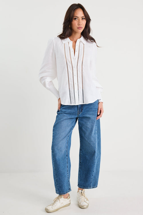 Woman wearing a white blouse and blue jeans on a white background