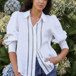 Woman wearing a white blouse with black trim in front of hydrangea flowers