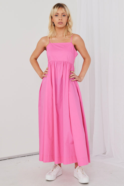 model posing in hot pink maxi dress and white sneakers