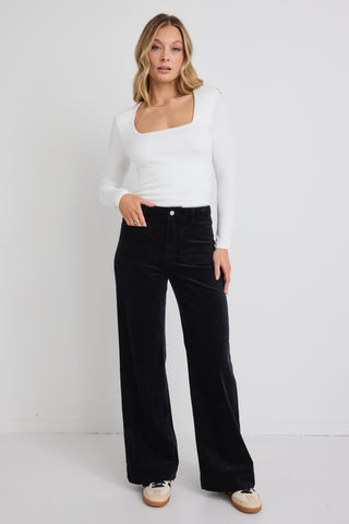 model wears white long sleeve top and black wide leg jeans with sneakers