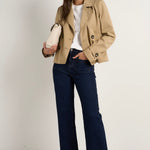 Model wears camel beige trench coat with dark indigo jeans