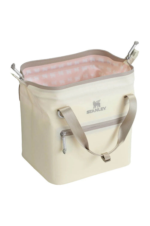 A cream-colored Stanley cooler bag with a light pink patterned interior lining, featuring dual beige shoulder straps and silver metal handles, shown on a solid white background.
