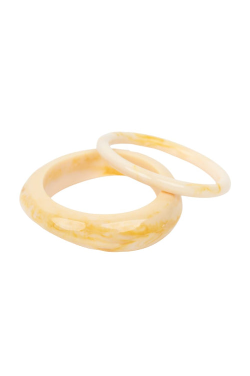 Two thick bangles with a marbled cream and yellow pattern, overlapping on a solid white background.