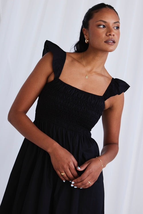 model wears a black dress with black sandals