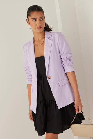 model wearing purple blazer over a black mini dress