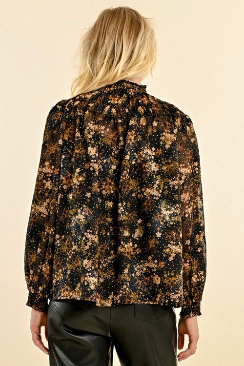 model wears a black and gold floral long sleeve blouse