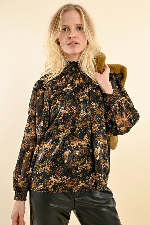 model wears a black and gold floral long sleeve blouse