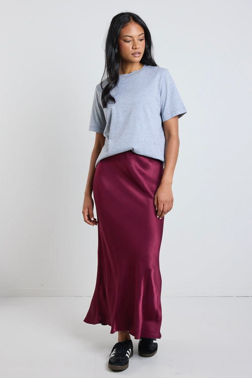 model wears grey t-shirt and a dark red satin skirt