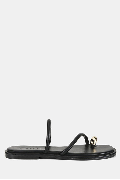 A single black flat thong sandal with a small gold-tone decorative ring on the toe strap, shown from a side profile against a light gray background.