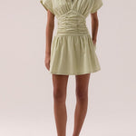 model wears a green ruched dress