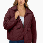Woman wearing a maroon quilted jacket on a white background