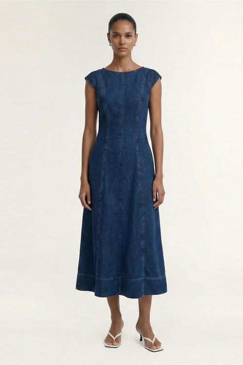 A woman modeling a sleeveless, below knee-length blue dress with a fitted waist and flared skirt, standing against a plain light background.