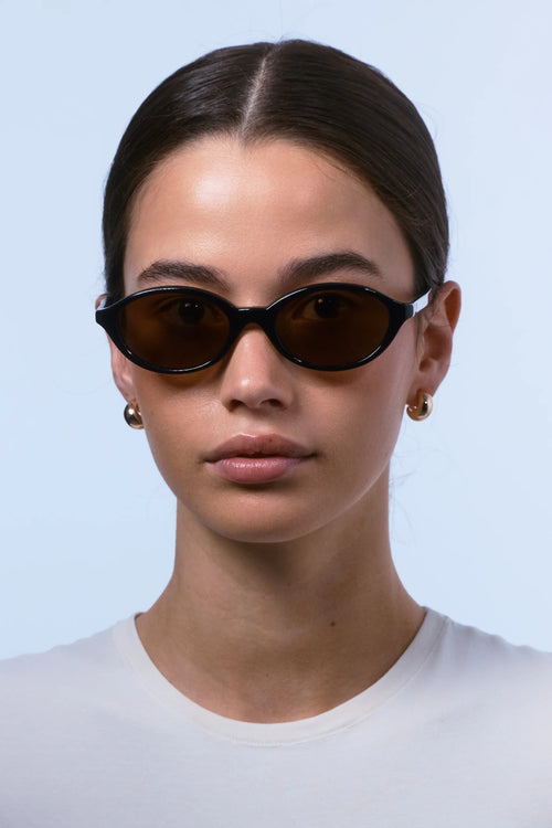 Woman wearing dark sunglasses against a light blue background