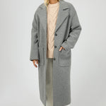 Woman wearing a long gray coat on a white background