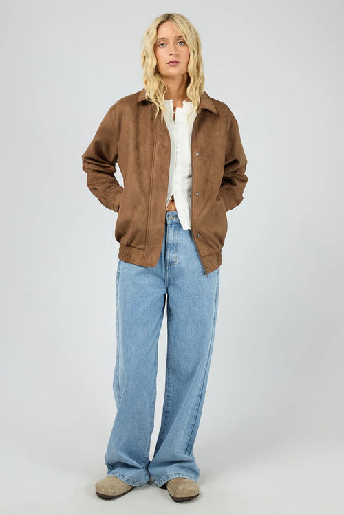 Person wearing a brown jacket, white shirt, and blue jeans on a white background