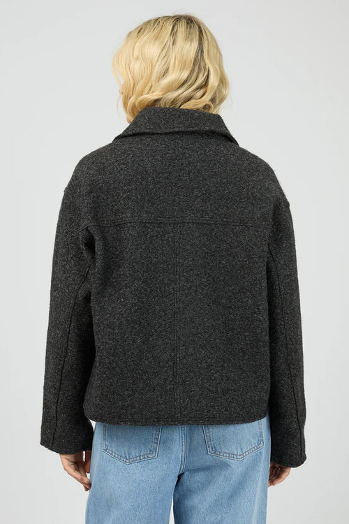 Person wearing a dark gray jacket and light blue jeans on a plain background
col_pattern