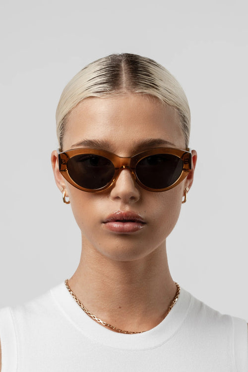 Woman wearing brown sunglasses against a plain background