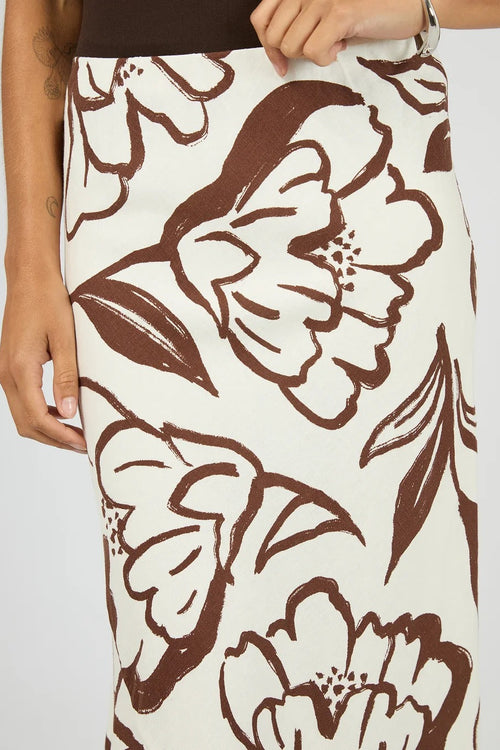 A close-up of a model wearing a high-waisted pencil skirt with a brown and cream floral pattern.
