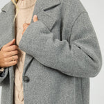 Person wearing a gray coat with a neutral background