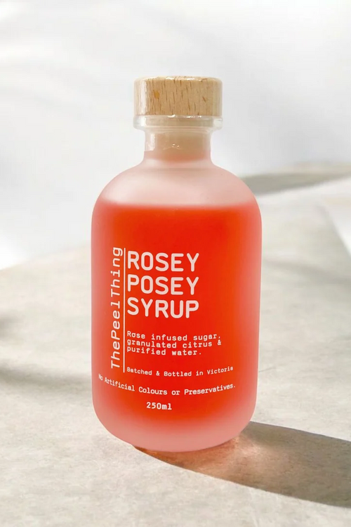 Bottle of 'Rosey Posey Syrup' on a light fabric background