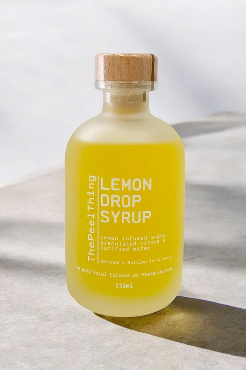 Bottle of lemon drop syrup with a wooden cap on a light fabric background