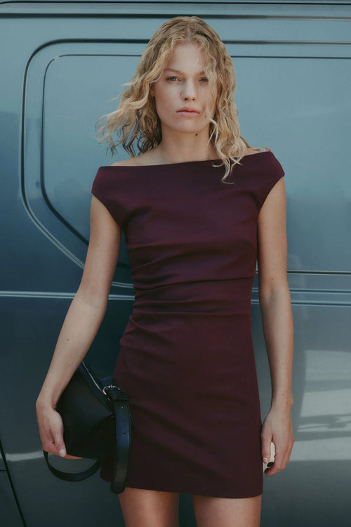 Woman in a burgundy dress standing next to a vehicle